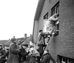 Inwoners worden gered uit hun woning. Soldaten en brandweer en politie helpen mee